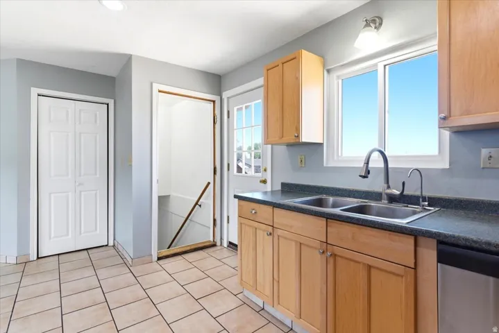 Kitchen with wood-finish cabinetry, a double basin sink with a high-arc faucet, and dark countertops