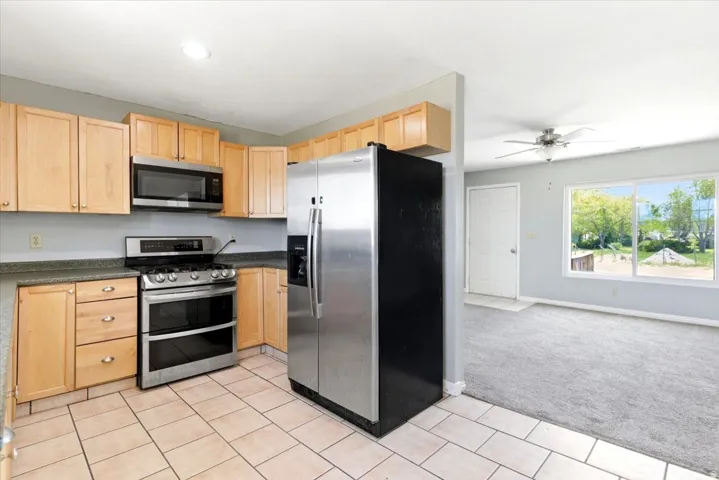 Kitchen featuring light wood cabinetry, stainless steel appliances, and tile flooring