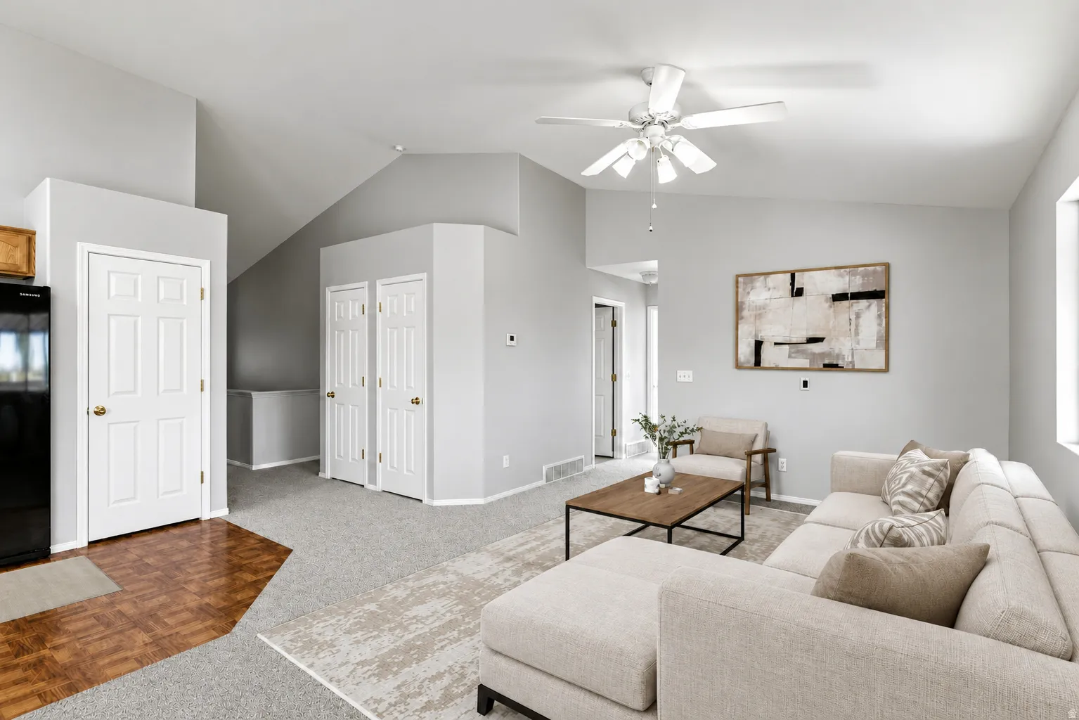 Spacious living area featuring vaulted ceilings, ceiling fan, and carpeted flooring
