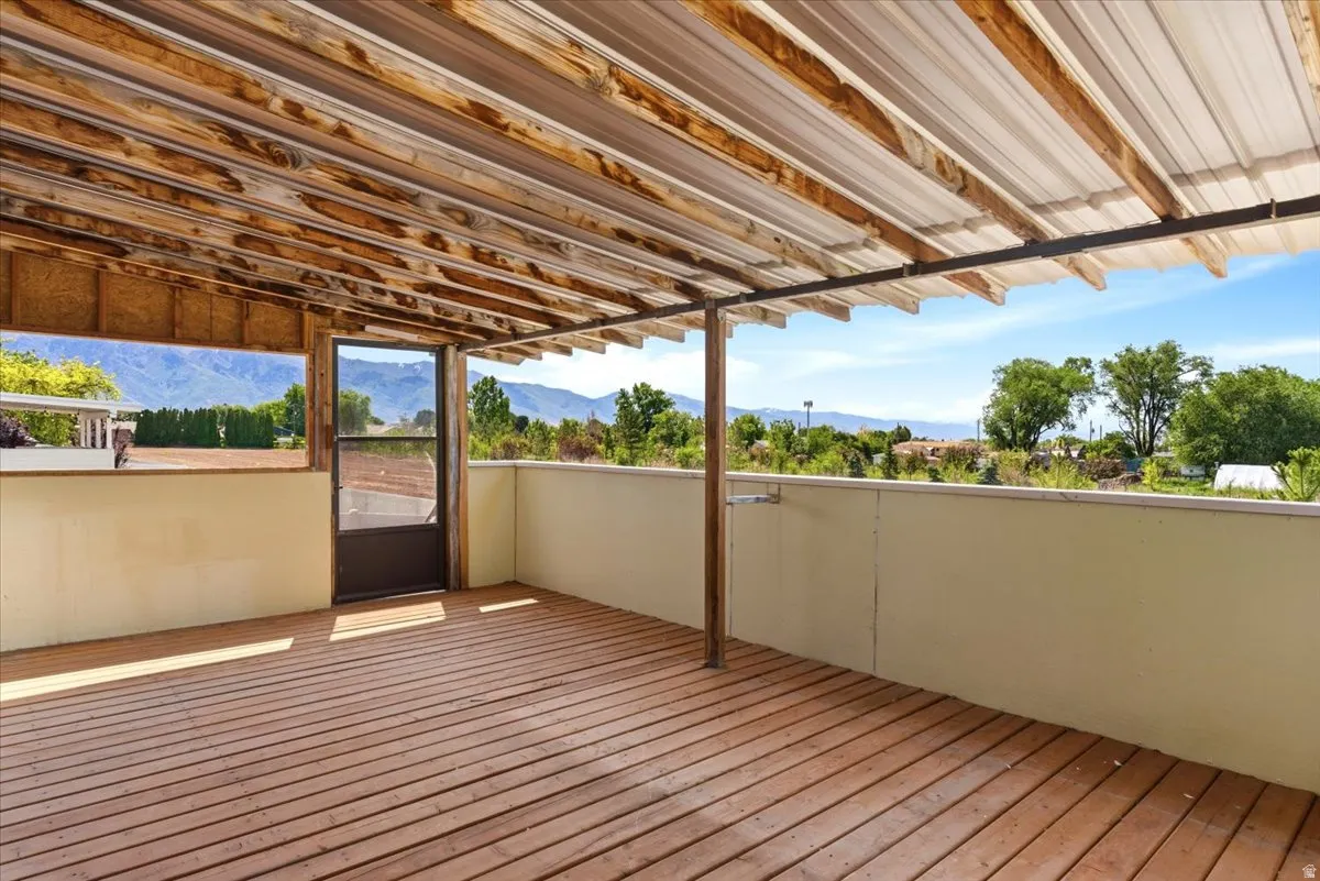 Spacious outdoor deck featuring wood-finish flooring, a corrugated metal roof, and durable light-colored railings