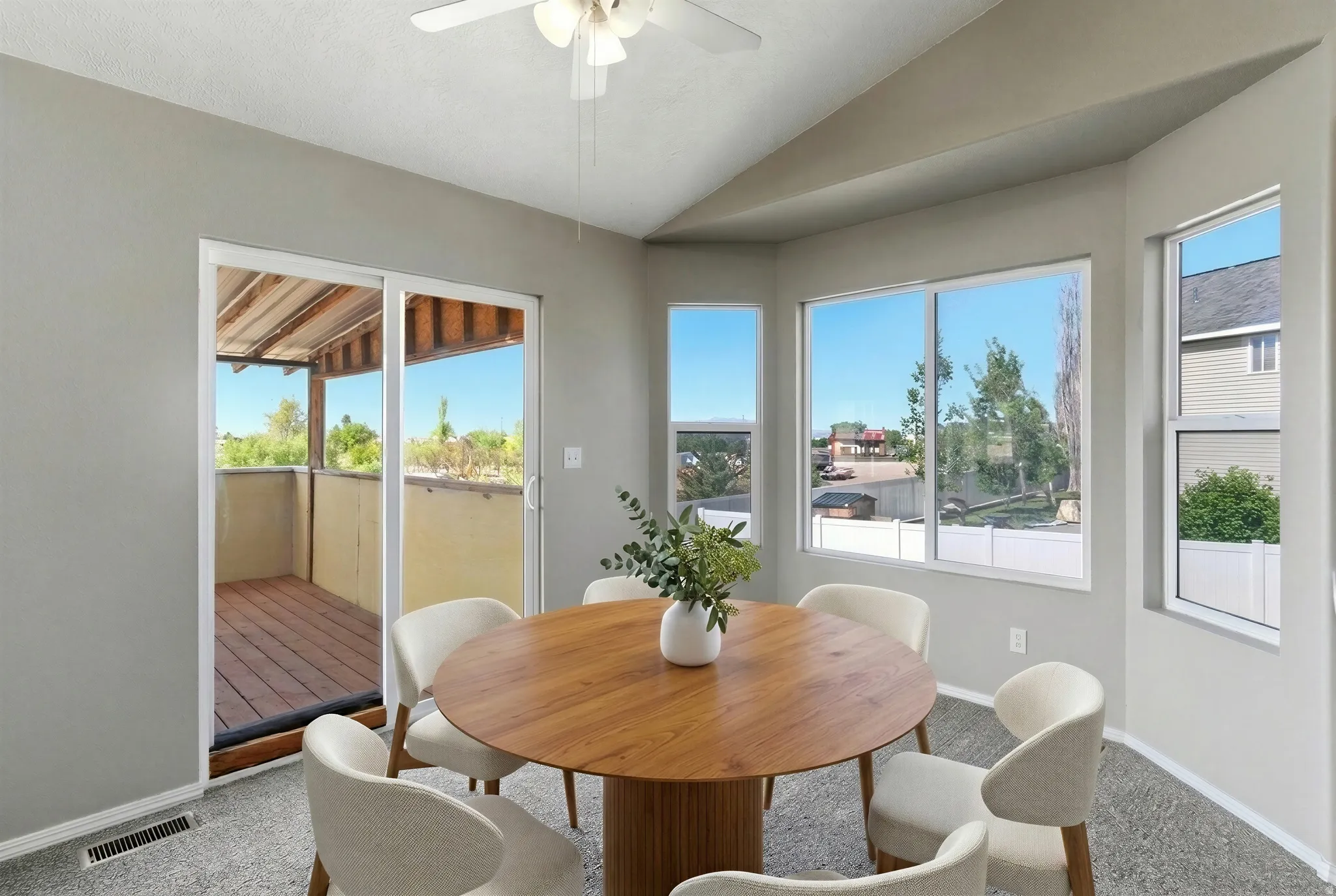 Carpeted interior space featuring a ceiling fan, a sliding glass door to an outdoor deck, and a multi-pane window configuration