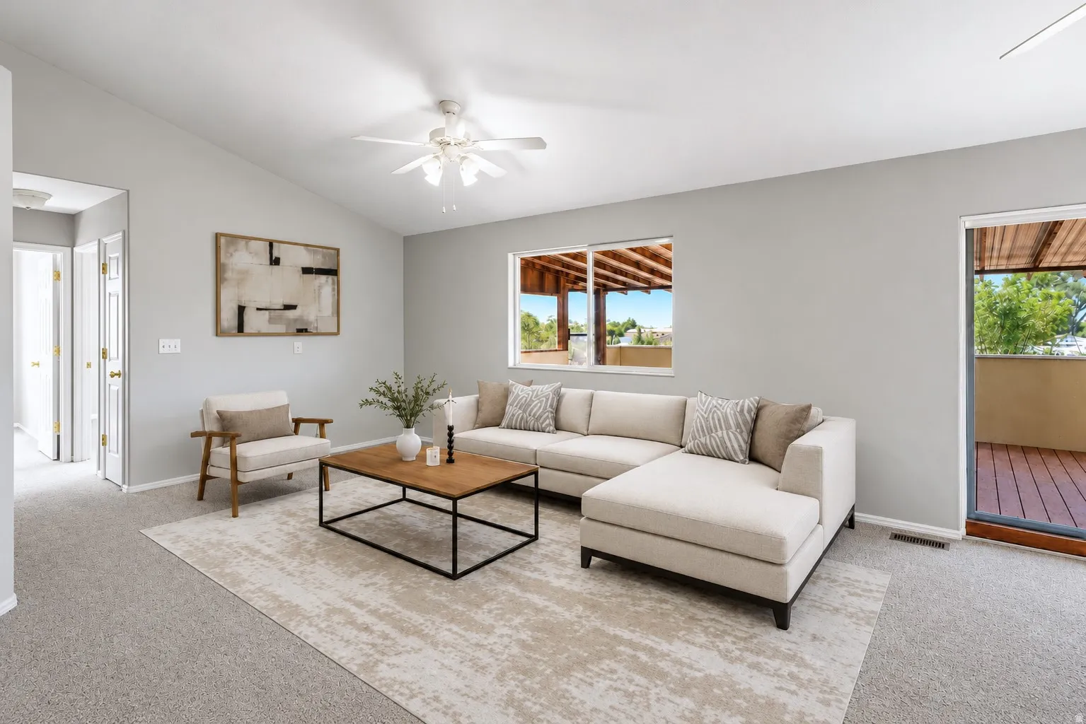 Bright living area featuring vaulted ceilings, a ceiling fan, and carpeted flooring