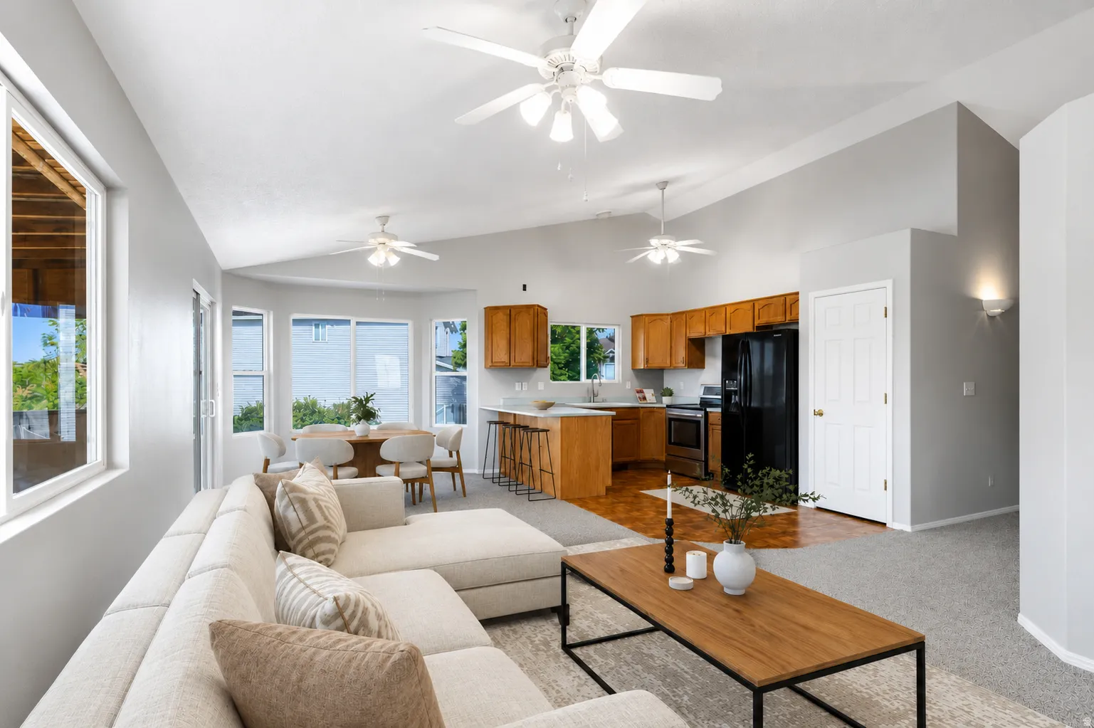 Open-concept living space featuring vaulted ceilings and multiple ceiling fans