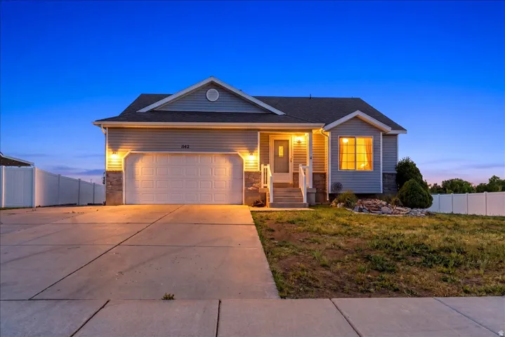 Exterior featuring light gray siding, stone accents, and a dual-car garage