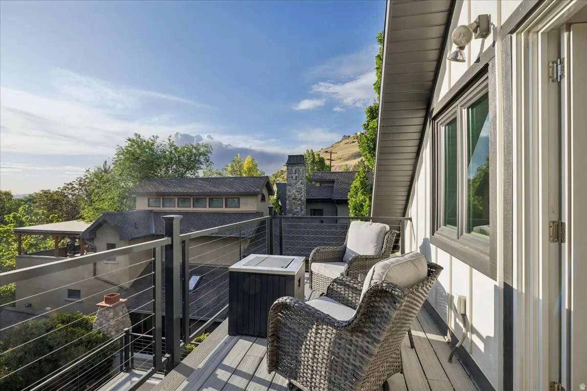 Exterior deck featuring composite wood-finish decking, dark gray cable railings, and a white vertical board and batten siding