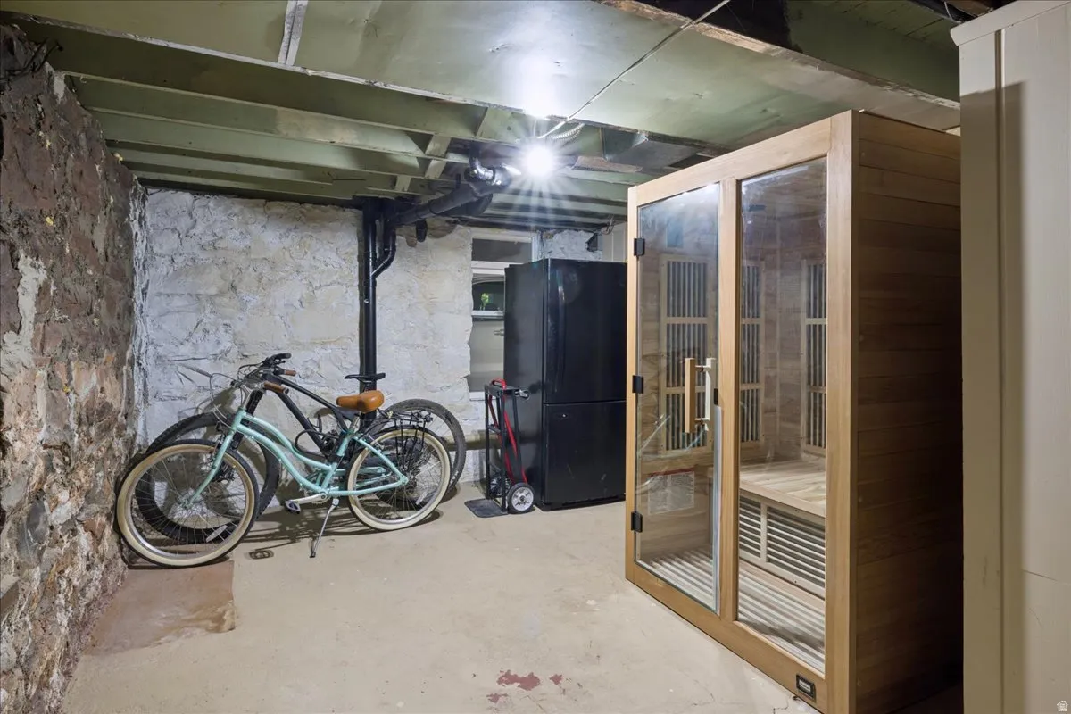 Basement space featuring a wood-paneled sauna with glass doors, a concrete floor, and exposed stone walls