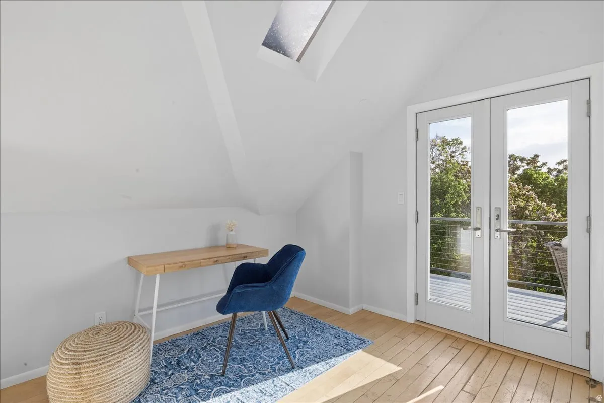 Attic room featuring a skylight, light wood-finish flooring, and bright white walls