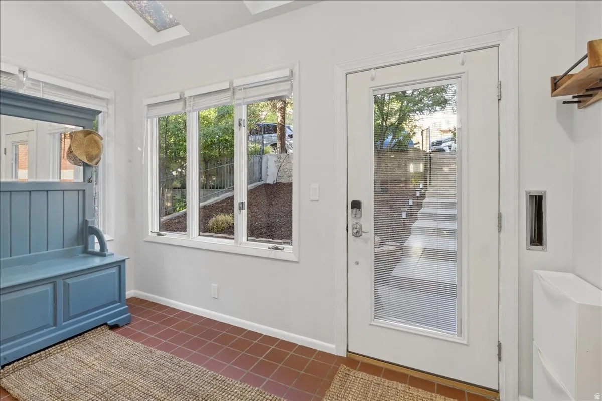Entryway with terracotta tile flooring, a clear glass paneled door, and three transom windows