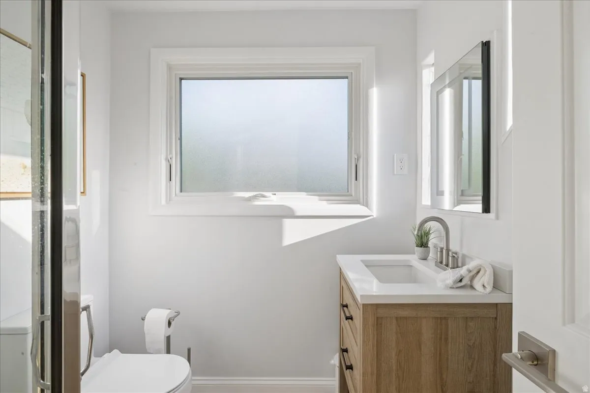 Bathroom featuring a wood-finish vanity with a white countertop, an undermount sink, and a brushed nickel faucet
