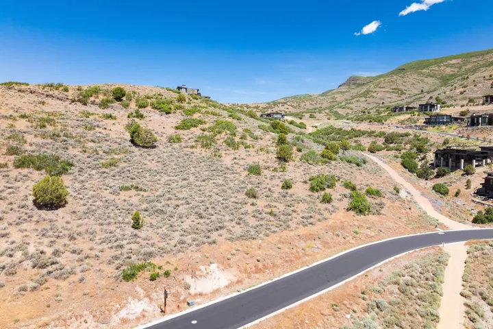 Rolling hillside terrain with established roads and surrounding residential structures