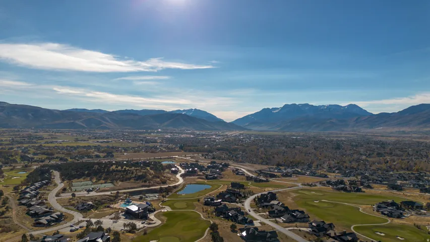 Expansive mountain scenery, golf course terrain, scattered residential properties, and a prominent body of water
