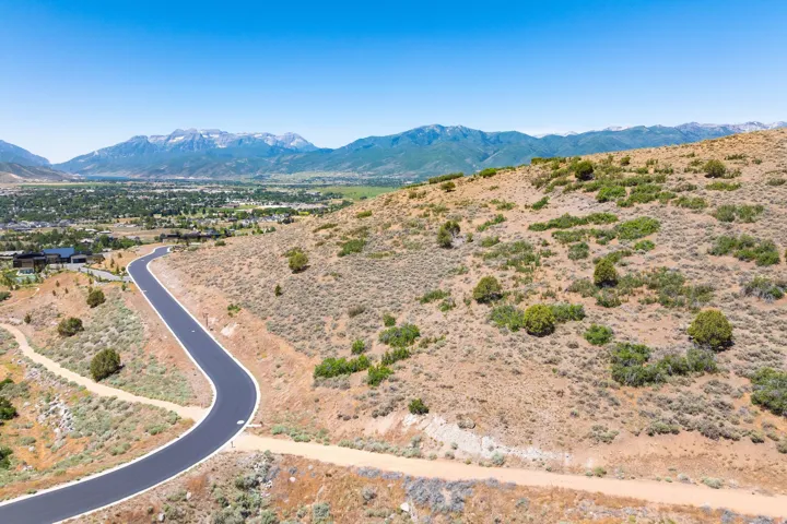 Paved roadway on a sloped, undeveloped parcel with distant mountain scenery