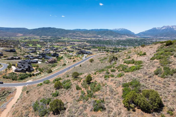 Expansive terrain featuring a paved road, scattered low-lying vegetation, and distant mountain ranges