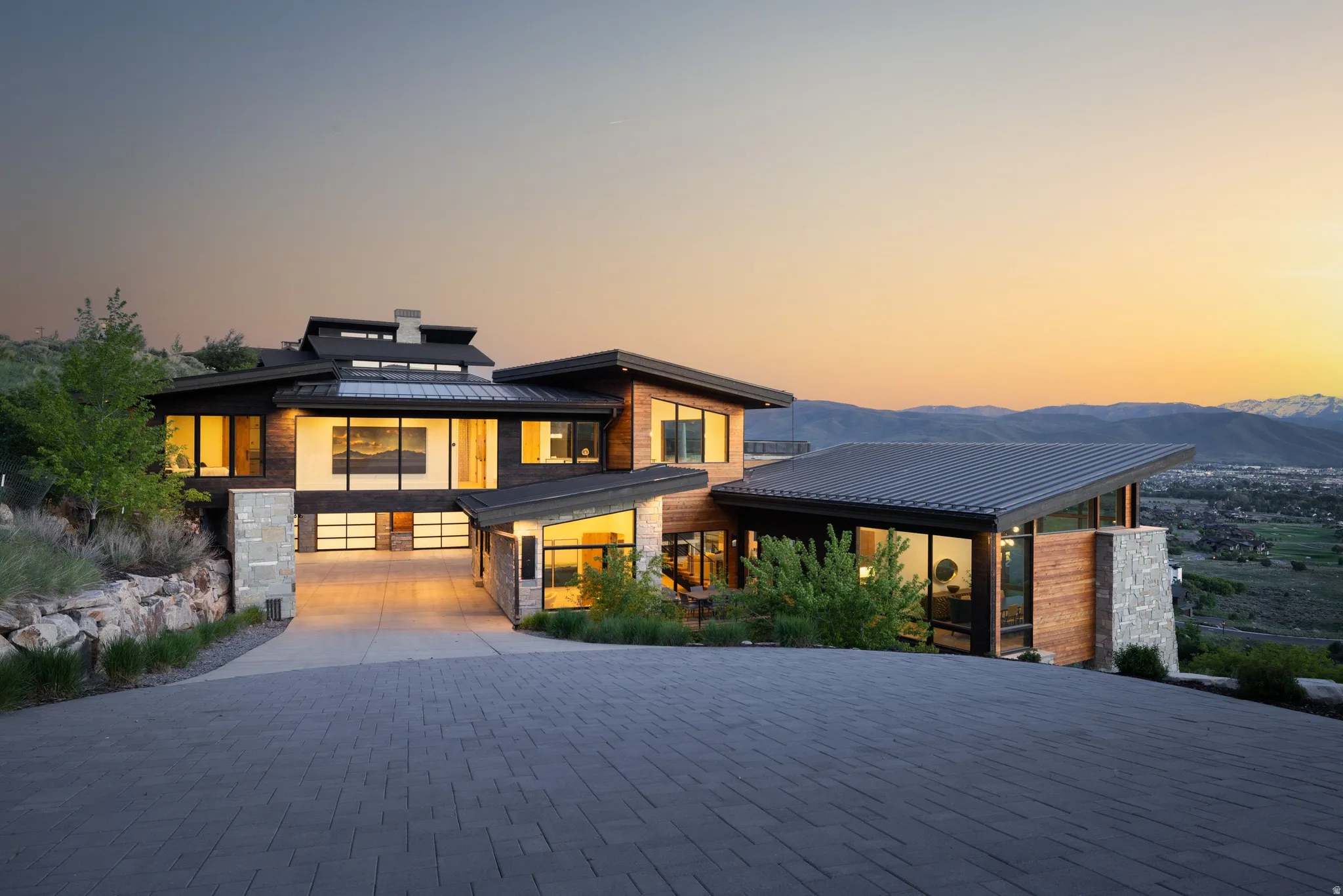 Modern architectural residence featuring a multi-level design, wood-finish siding, and stone accents