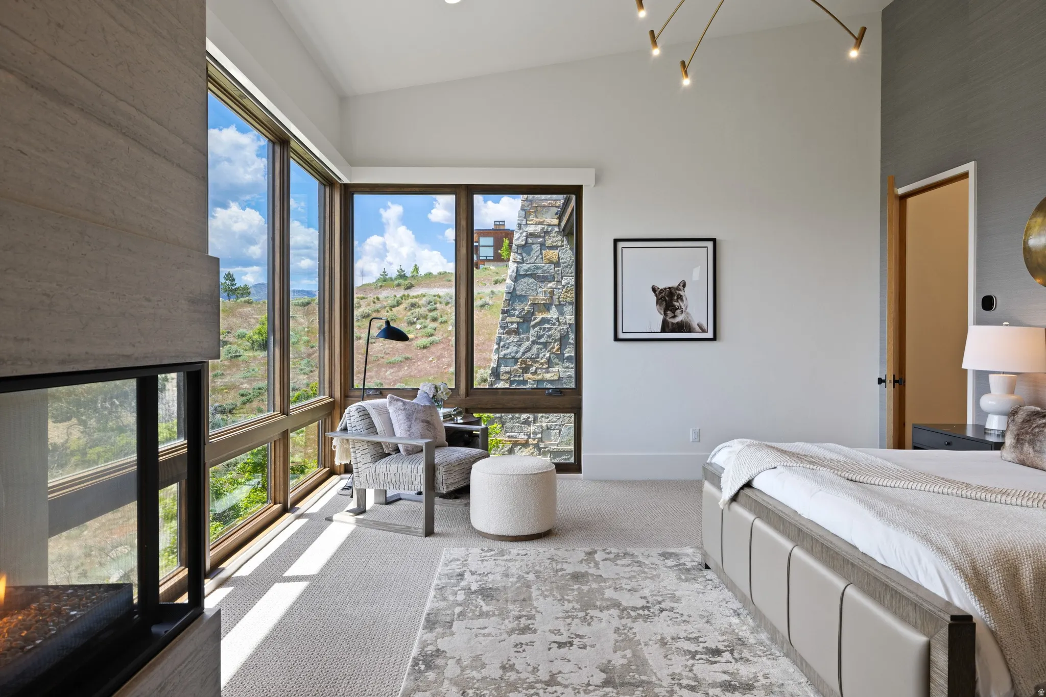 Expansive window wall with natural wood frames, stone architectural features, and an integrated fireplace