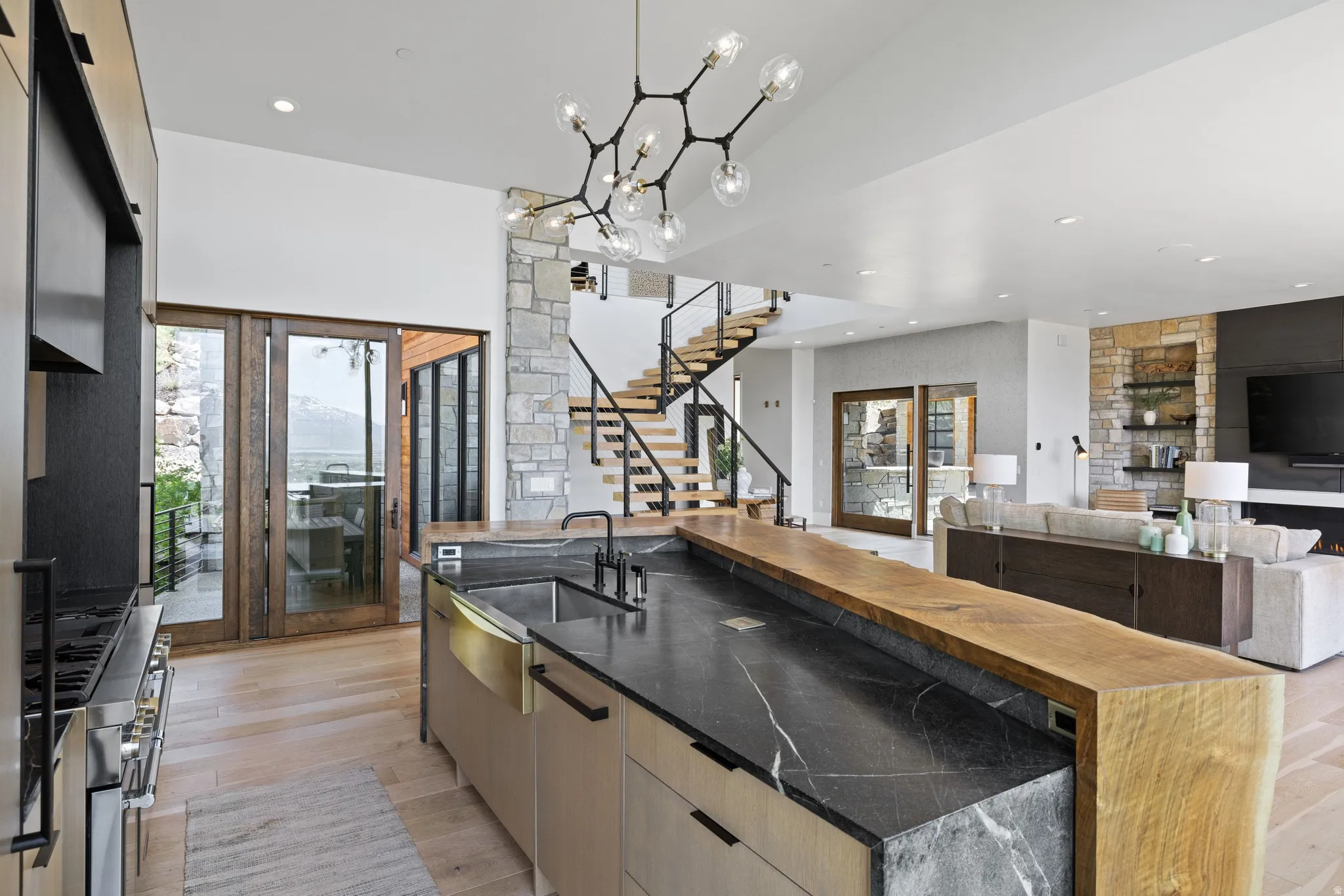 Modern kitchen island featuring a black veined countertop, an undermount sink, and a live-edge wood breakfast bar