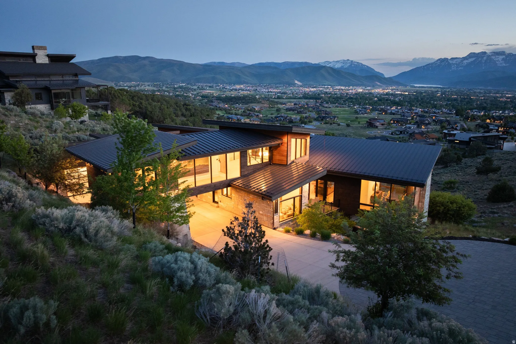 Modern architectural residence featuring extensive glazing, stone accents, multiple levels, and a metal roof