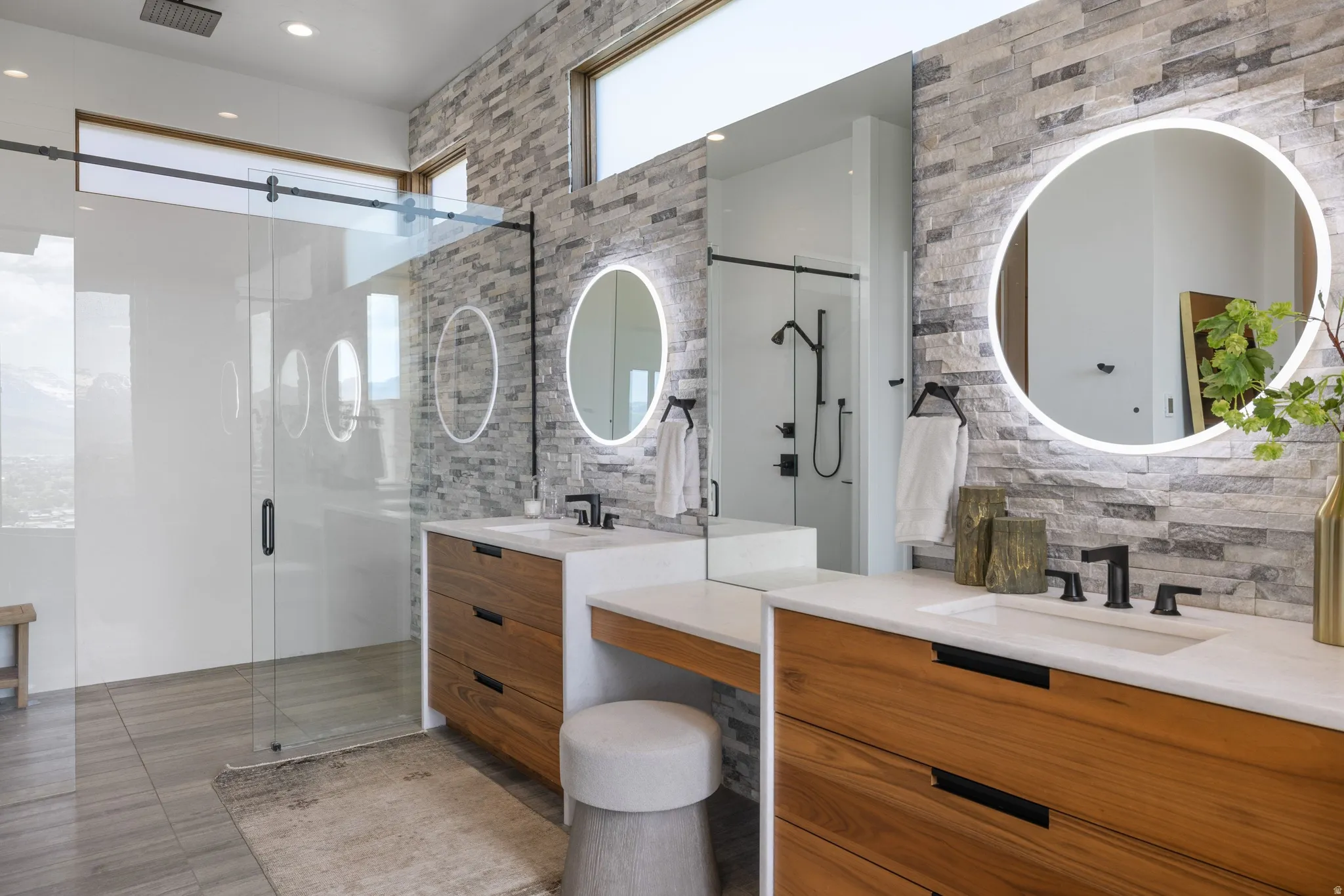 Dual wood-finish vanities with undermount sinks and white countertops, accented by circular backlit mirrors