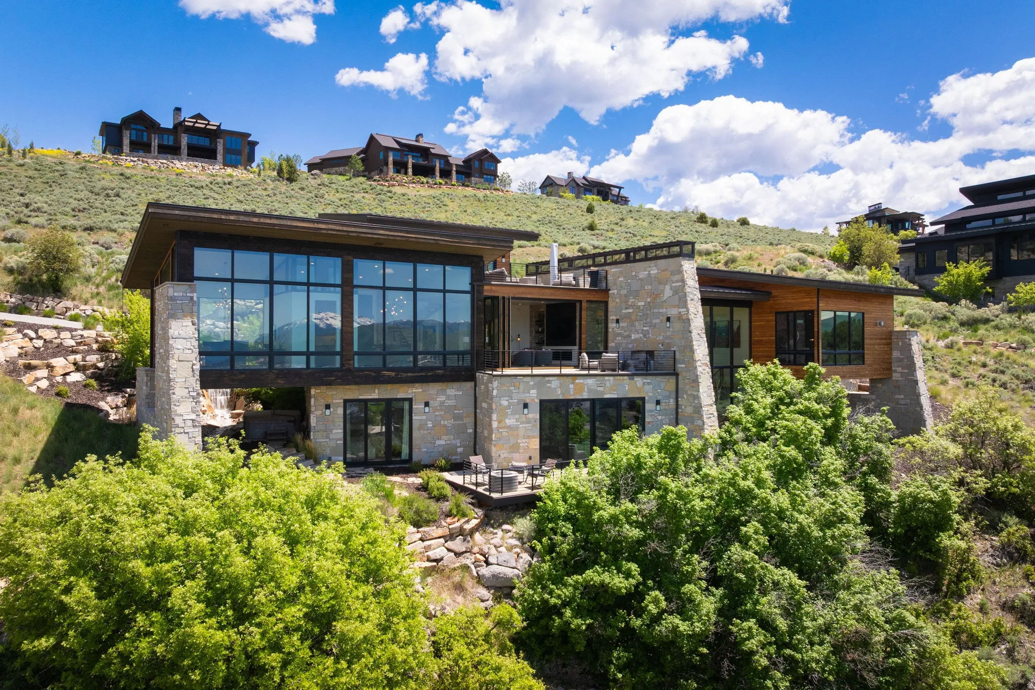 Contemporary hillside residence featuring stone and wood-panel exterior accents