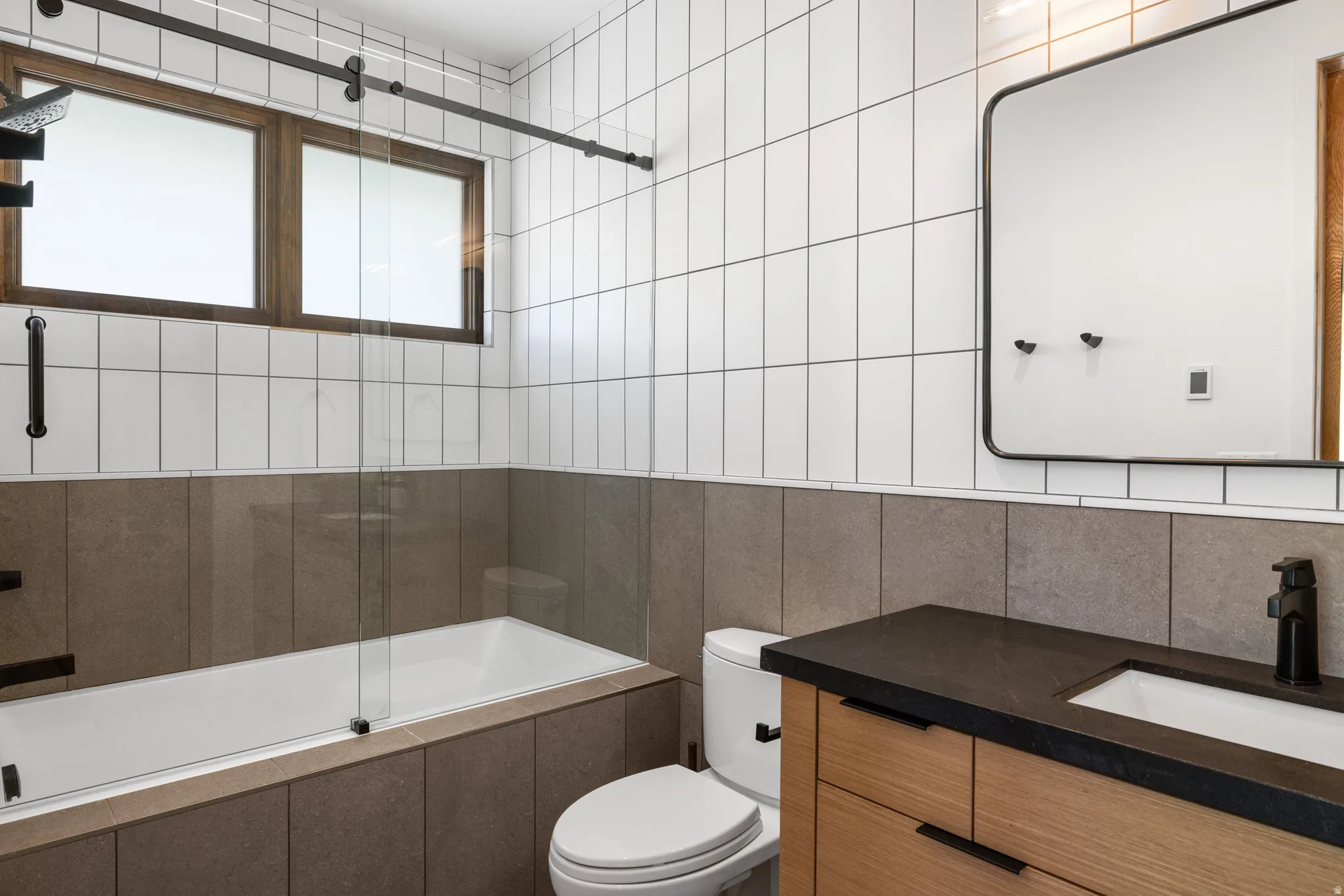Bathroom featuring a wall-mounted vanity with wood-finish cabinetry, a dark countertop, and a rectangular sink