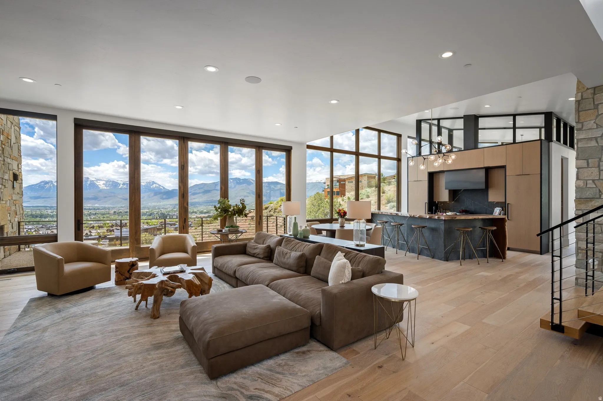 Open-concept living space with a stone accent wall and large format wood-finish plank flooring