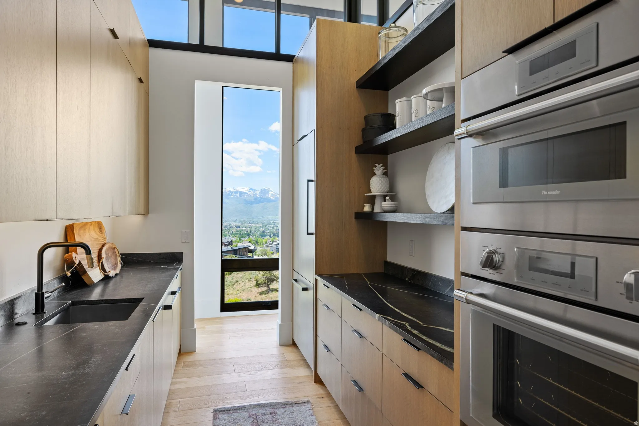 Contemporary kitchen featuring light wood-finish cabinetry and paneled appliances