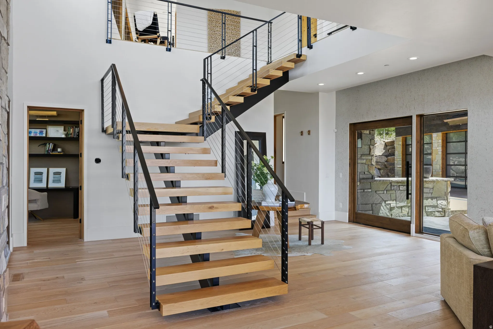 Modern open-tread staircase with wood risers, black metal railings, and cable infill