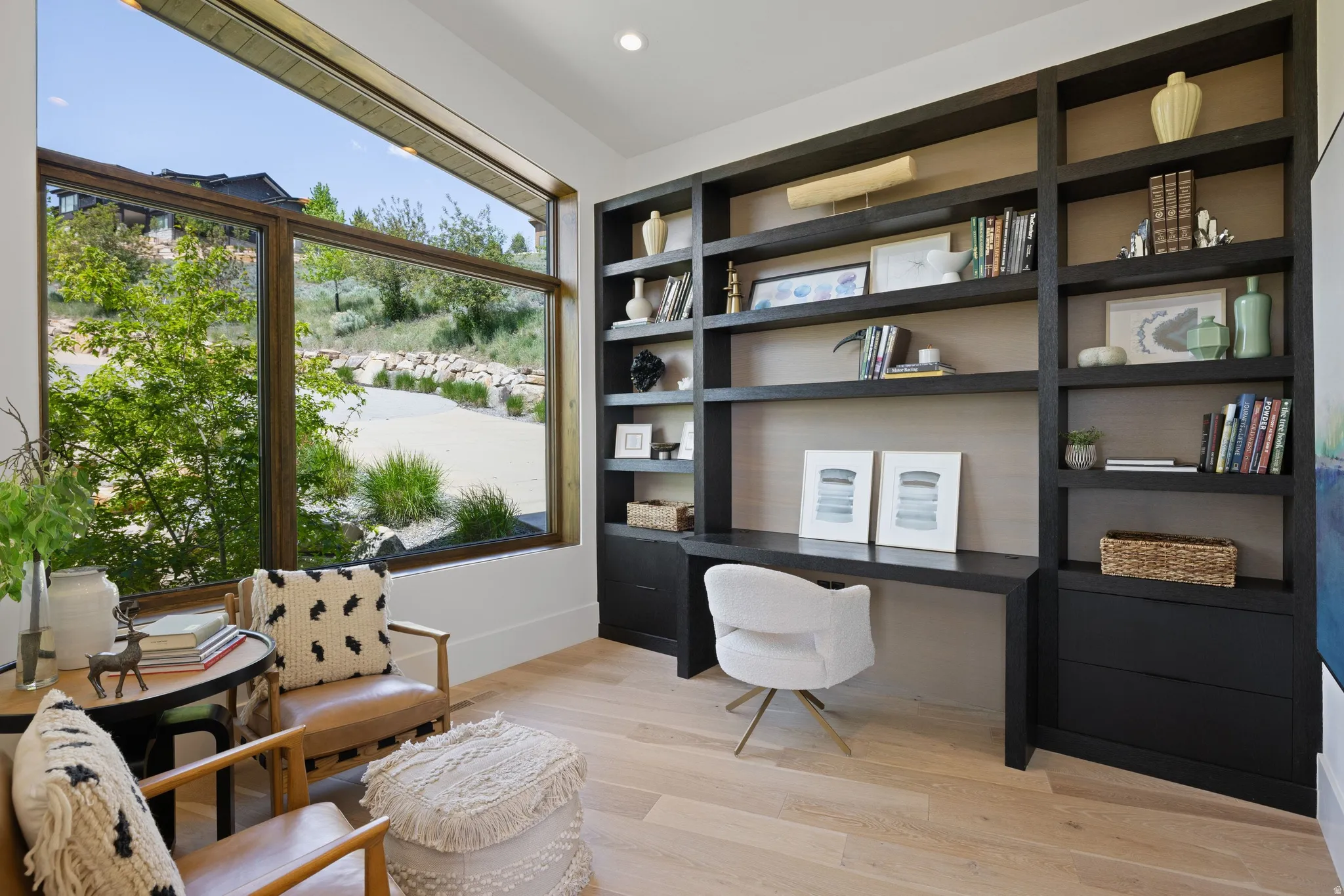 Built-in dark wood shelving and desk unit featuring integrated lighting and drawer storage