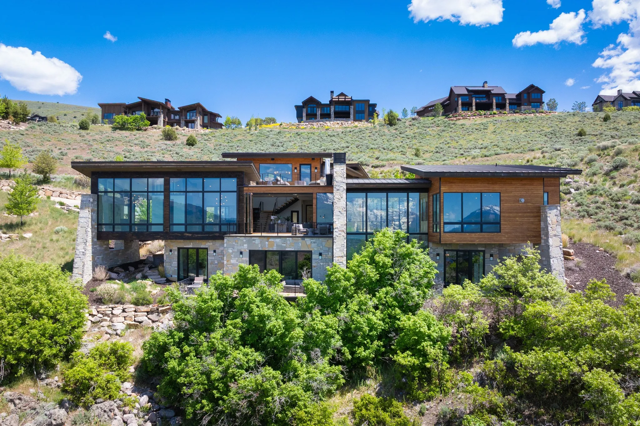 Modern architectural design featuring expansive glass panels, natural wood siding, and stone accents