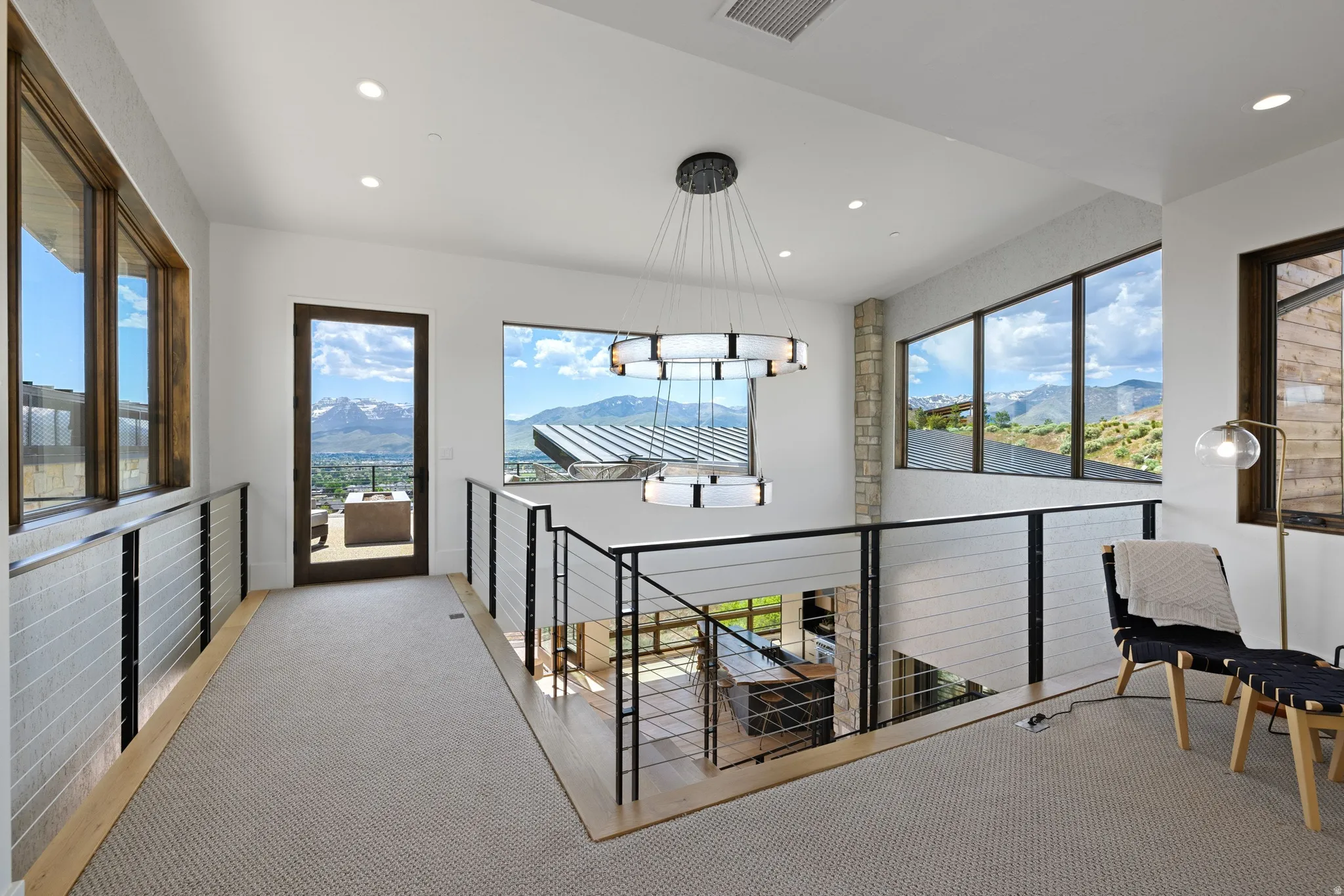 Upper-level landing featuring a contemporary chandelier, recessed lighting, and large windows