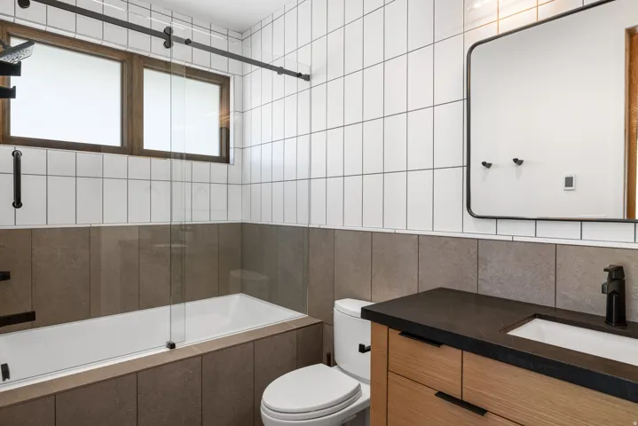 Bathroom featuring a wall-mounted vanity with wood-finish cabinetry, a dark countertop, and a rectangular sink