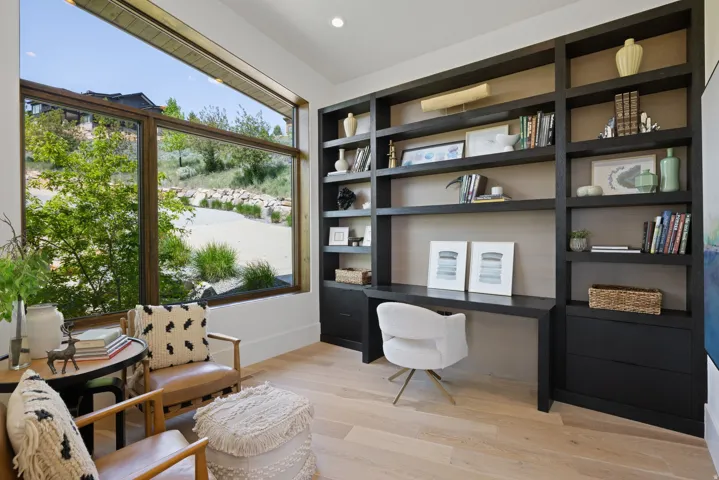 Built-in dark wood shelving and desk unit featuring integrated lighting and drawer storage