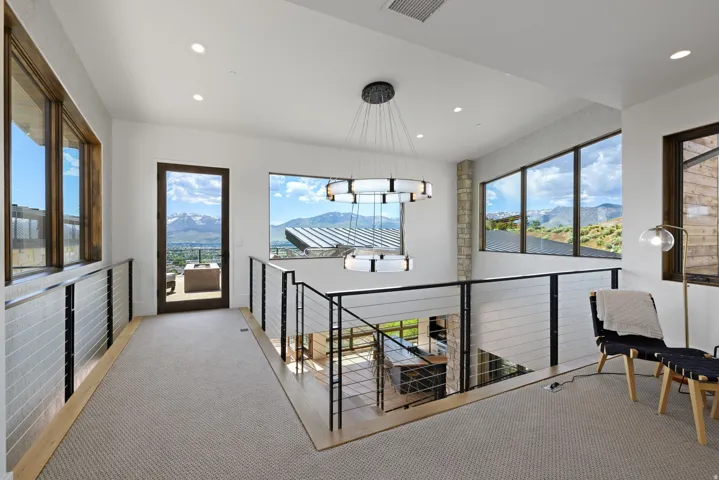 Upper-level landing featuring a contemporary chandelier, recessed lighting, and large windows