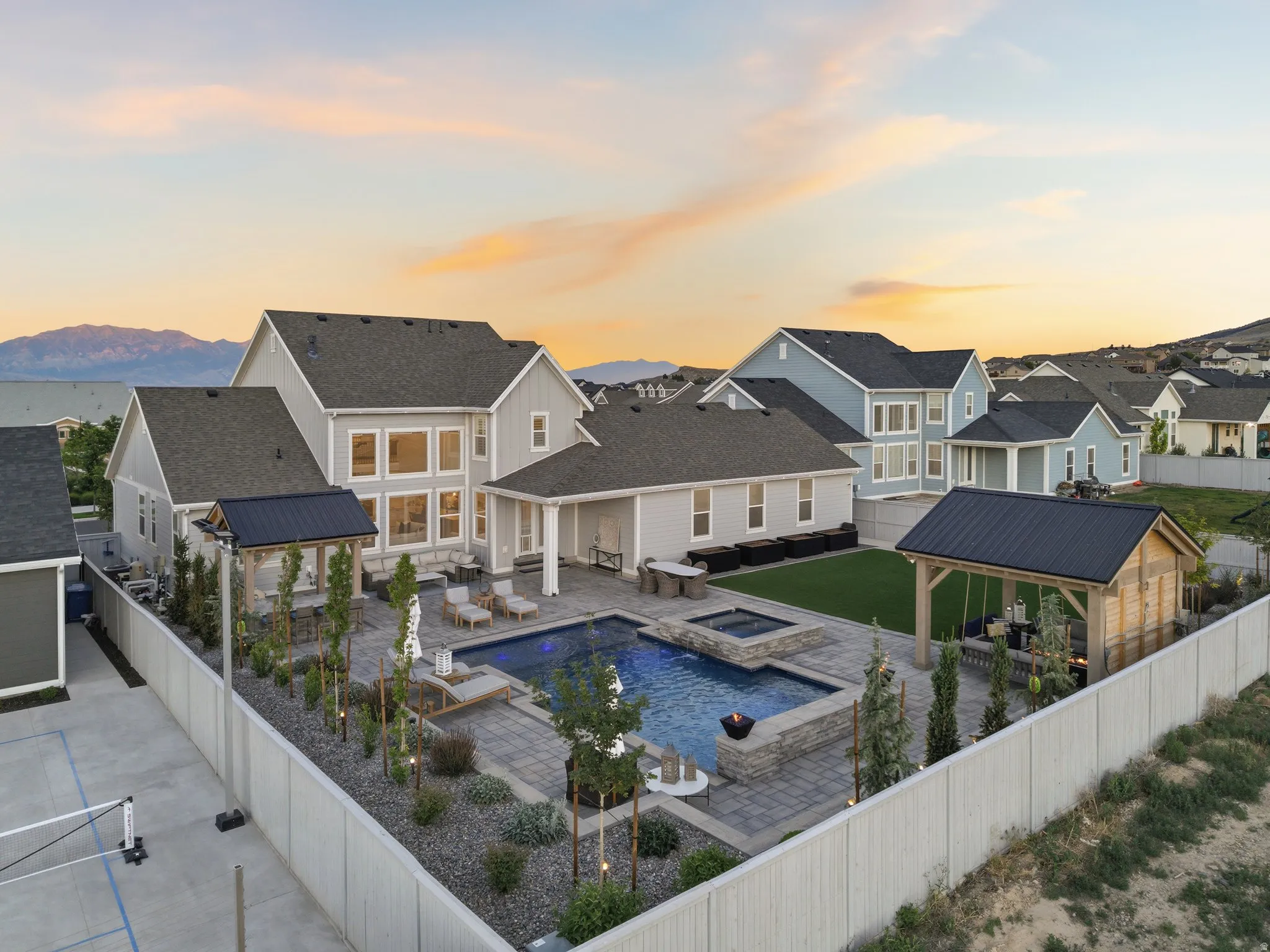 Expansive backyard featuring a rectangular swimming pool with a raised spa, paver patio, and low-maintenance landscaping