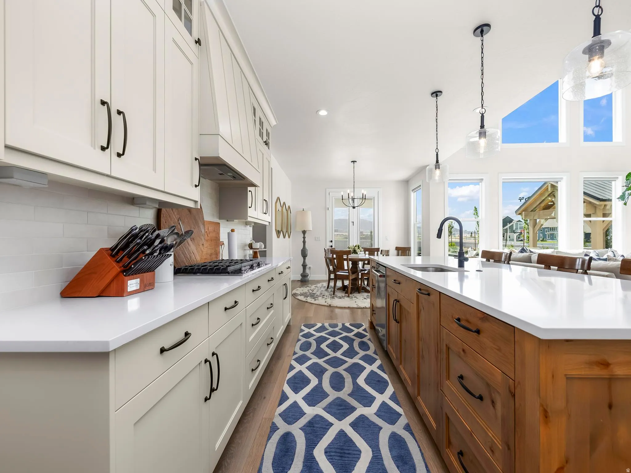Open-concept kitchen featuring two-tone cabinetry, a large island with sink, and white countertops