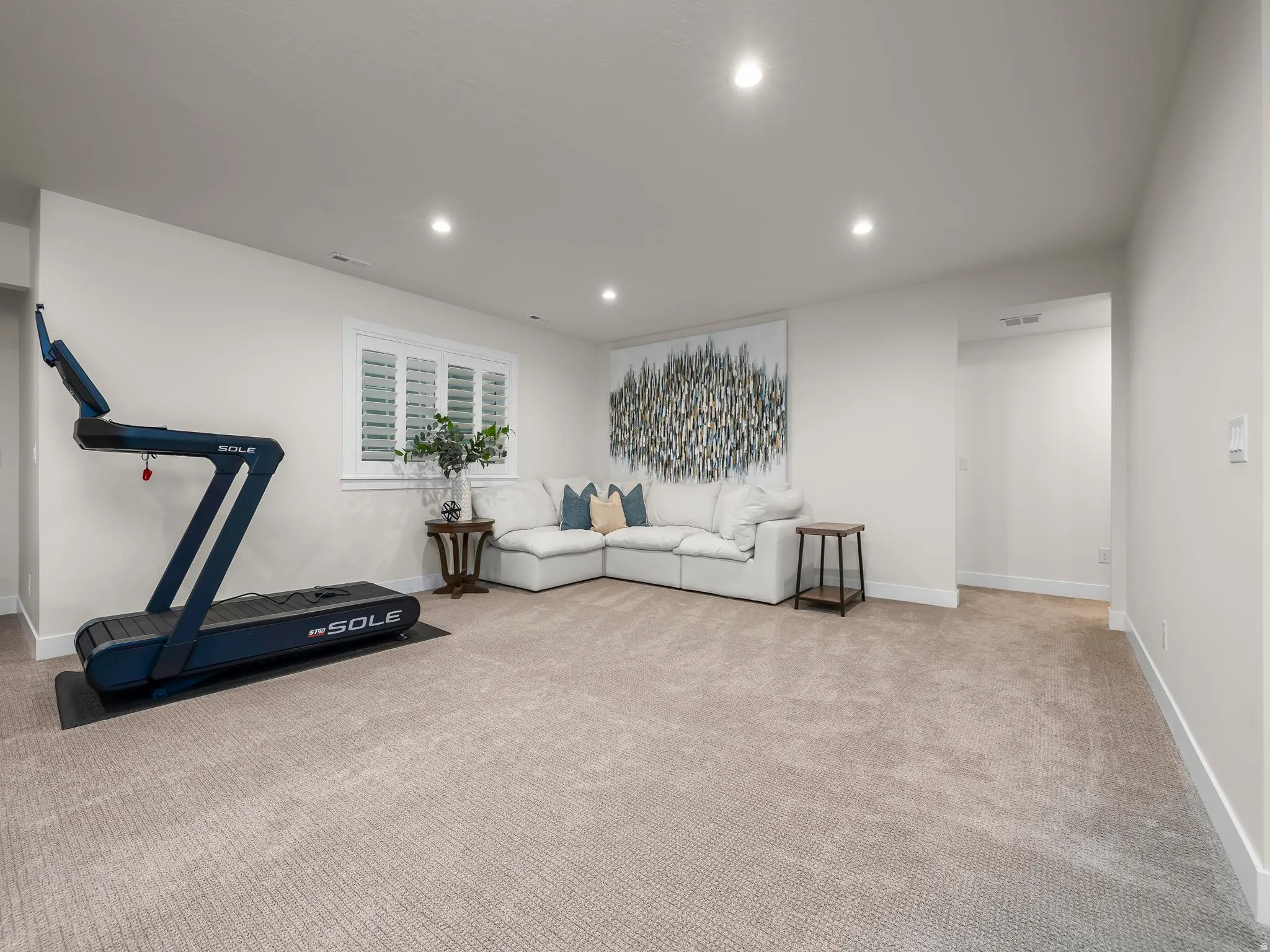 Spacious carpeted room featuring recessed lighting, a window with white plantation shutters, and light-toned walls