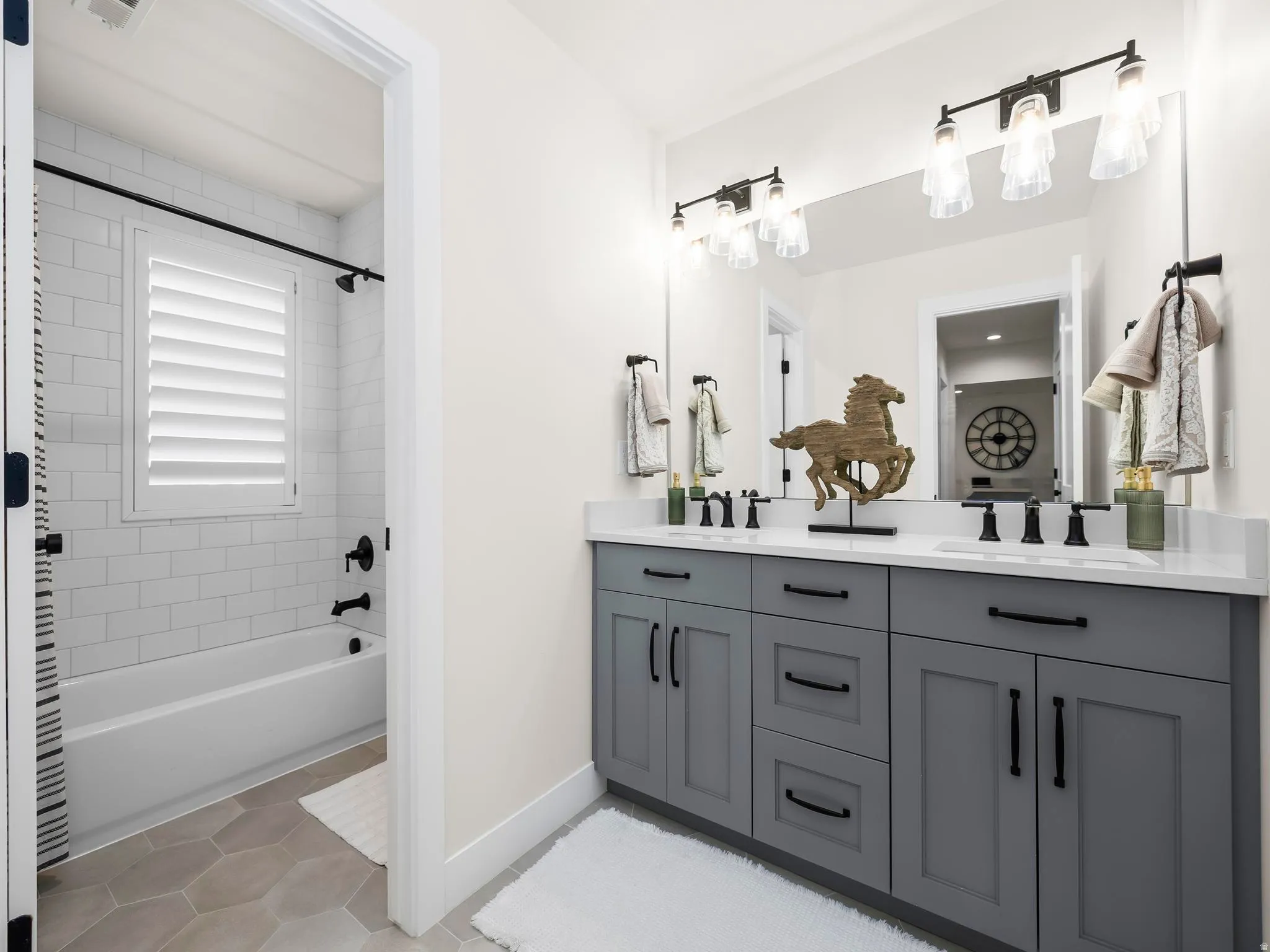 Double vanity with shaker-style cabinetry, matte black hardware, and an expansive mirror