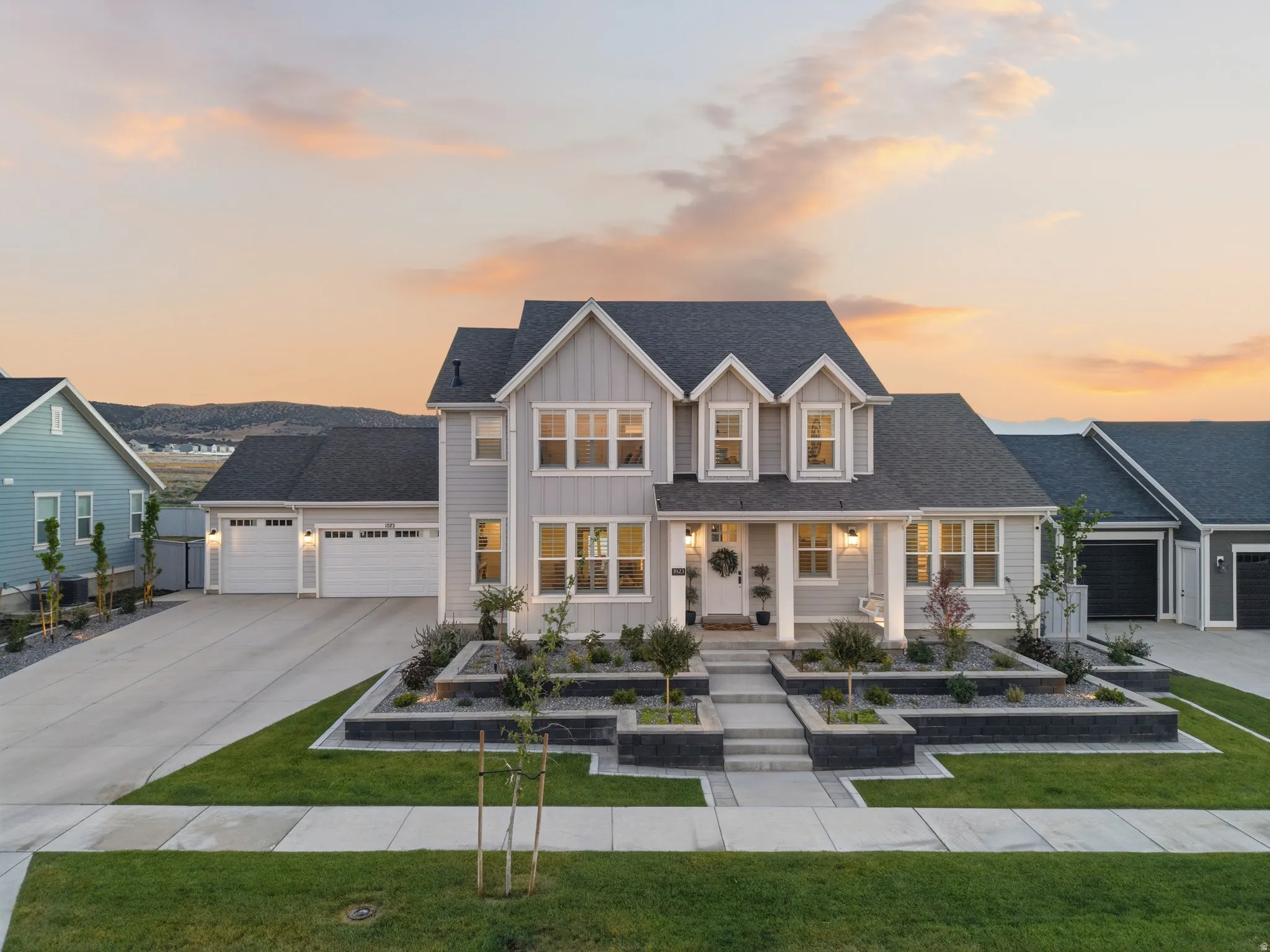 Contemporary exterior with light gray siding, dark shingle roof, and multiple dormer windows