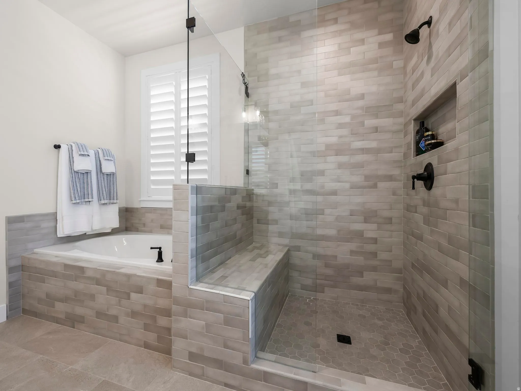 Spacious bathroom featuring a glass-enclosed shower with a built-in bench and recessed niche