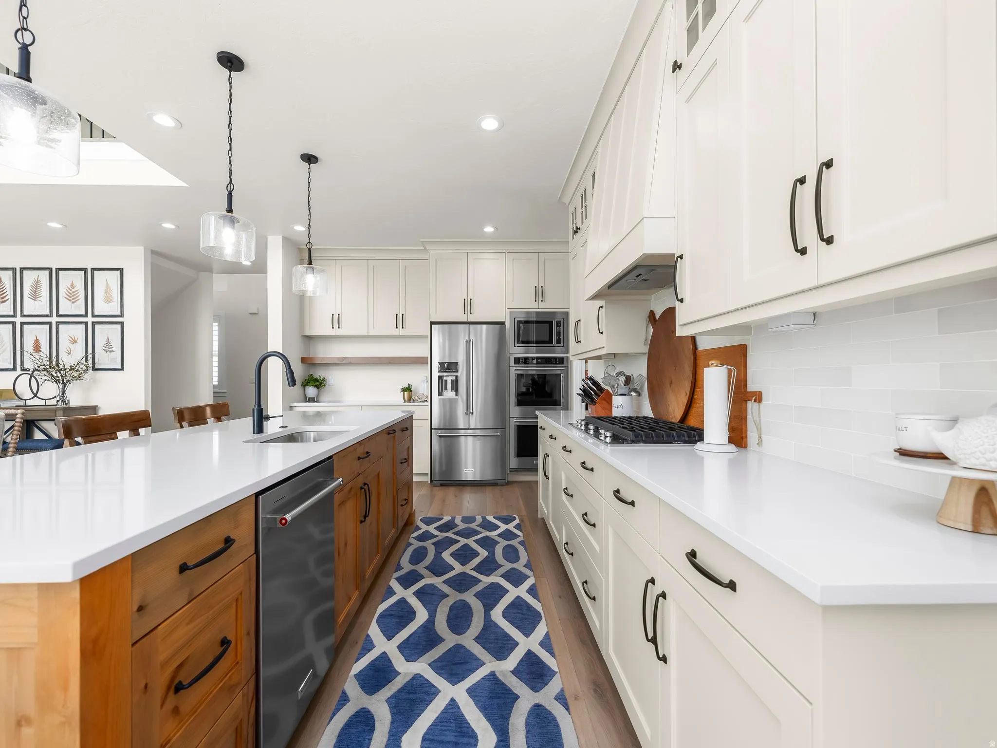 Contemporary kitchen featuring an expansive center island with integrated sink, stainless steel dishwasher, and natural wood-finish cabinetry