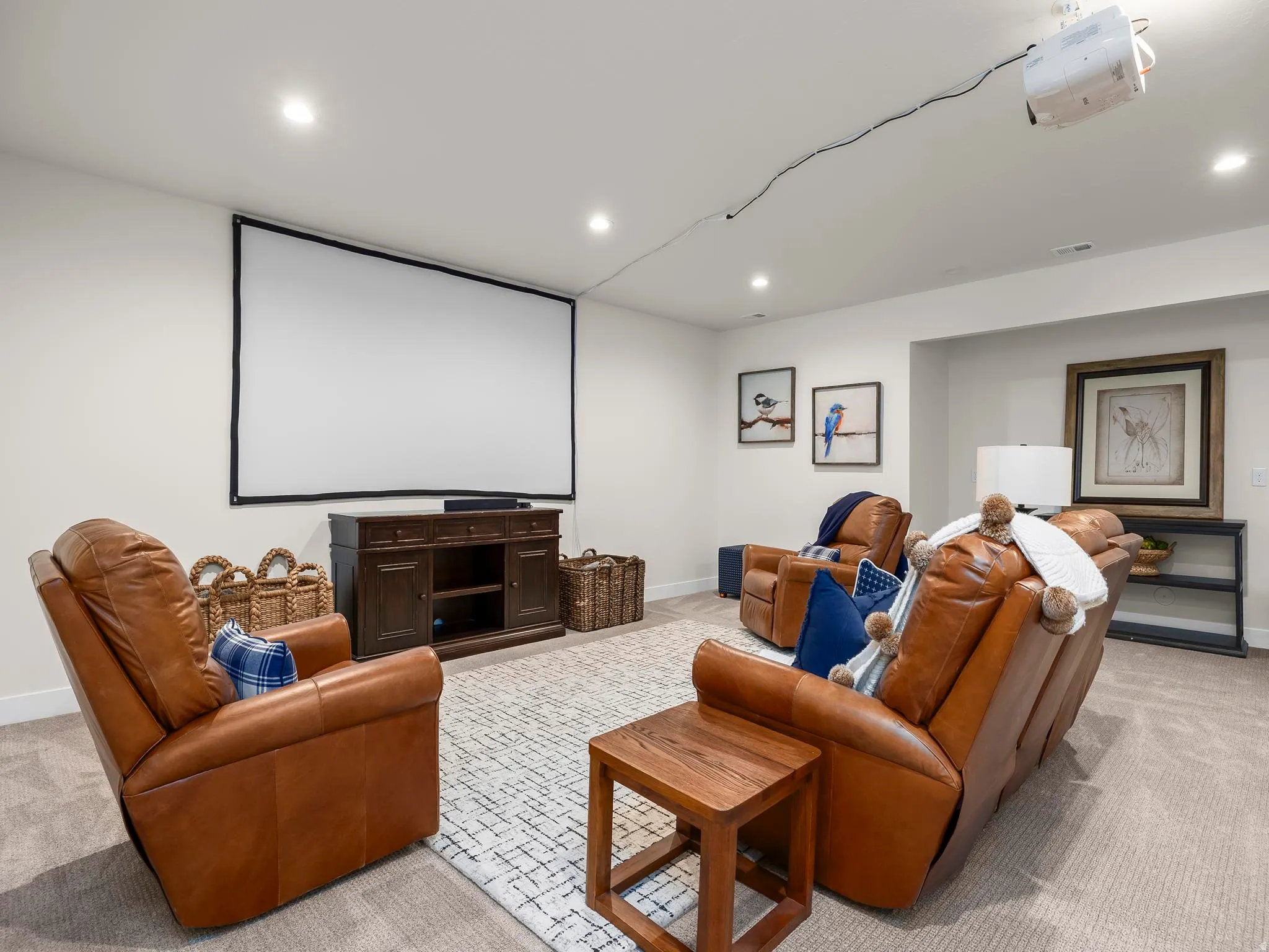 Dedicated media room featuring a large projection screen, recessed ceiling lighting, and soft carpet flooring