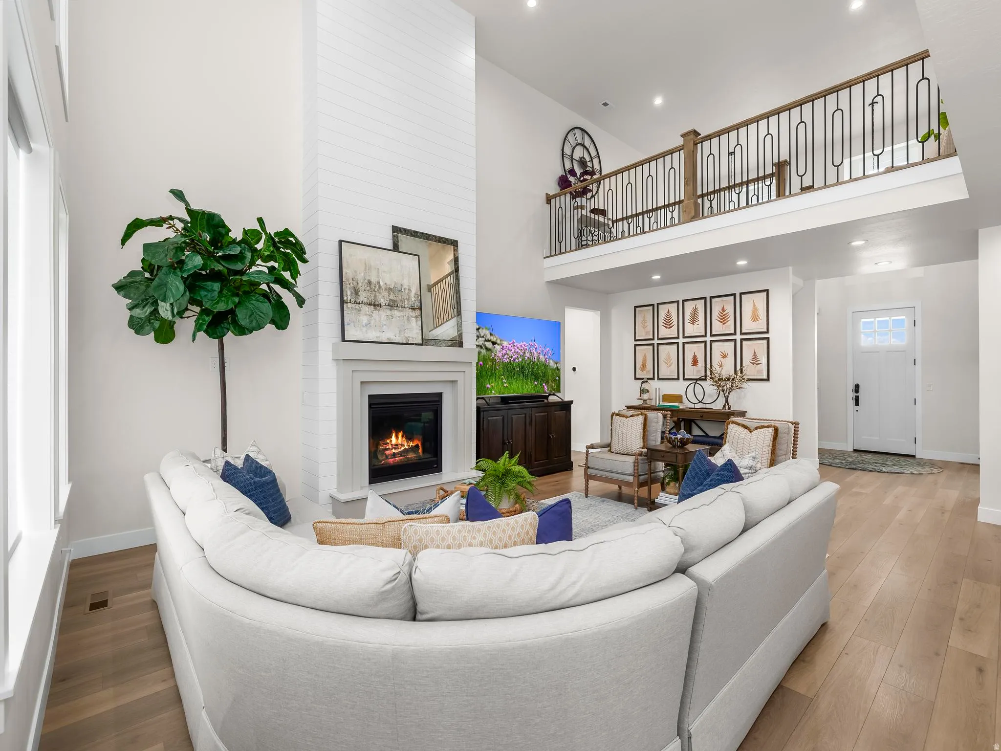 Spacious living area featuring a vaulted ceiling, a white brick fireplace, and wood-finish flooring