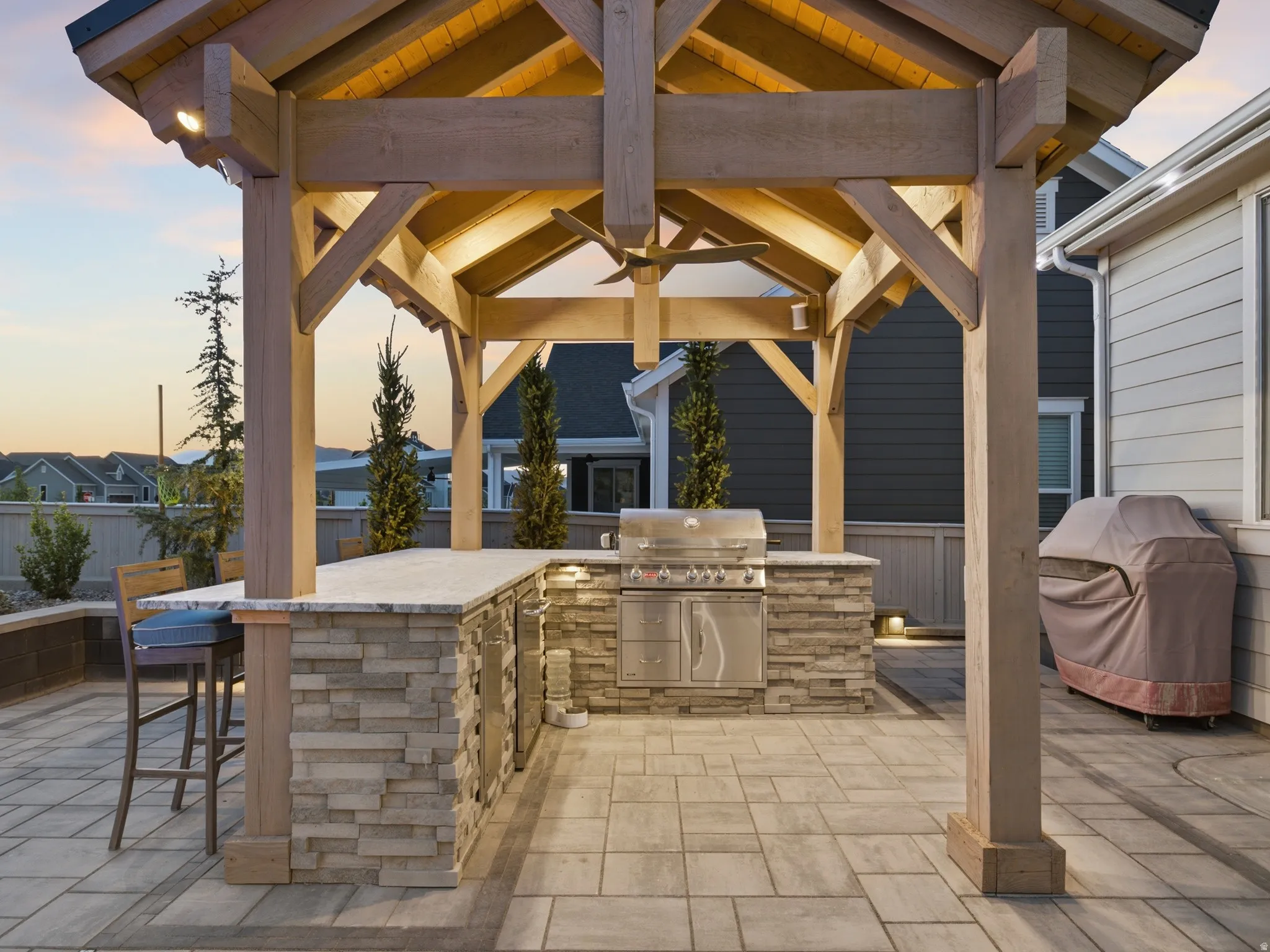 Outdoor kitchen featuring a built-in stainless steel grill, stone veneer base, and a light-toned countertop