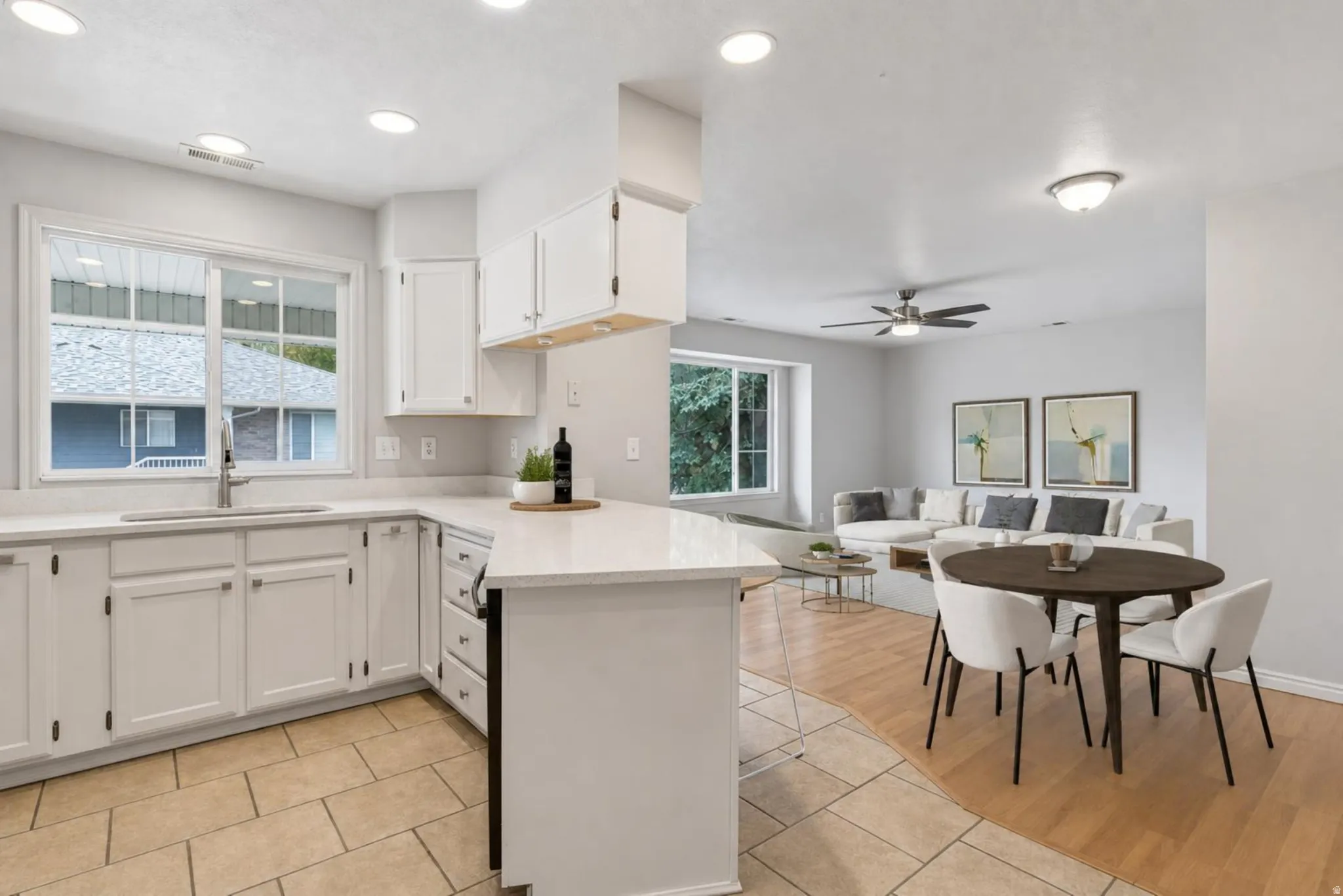 Open-concept kitchen featuring white cabinetry, light-toned countertops, and a stainless steel sink with a gooseneck faucet