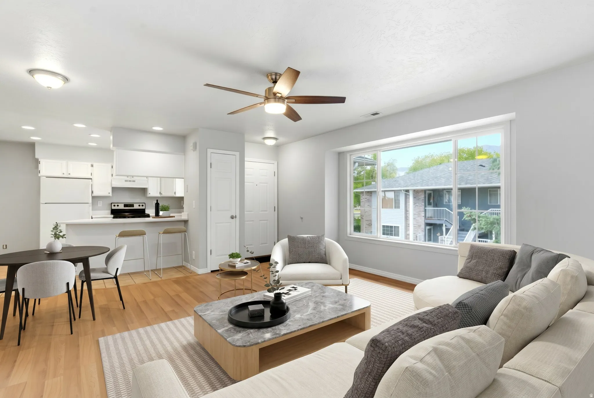 Open-concept living space featuring wood-finish flooring, a contemporary ceiling fan, and a large picture window