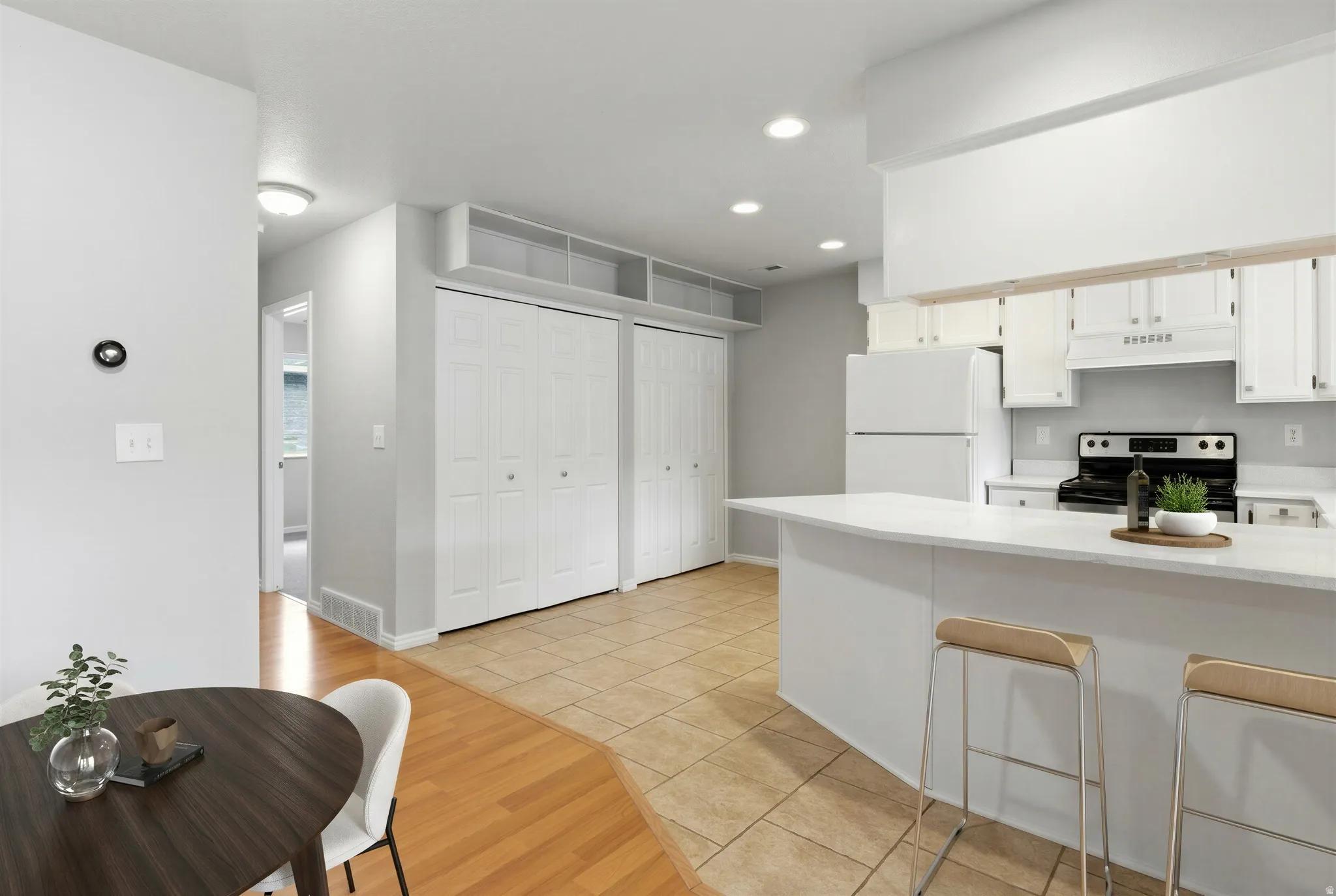 Open-concept kitchen featuring white cabinetry and appliances, a breakfast bar, and recessed lighting