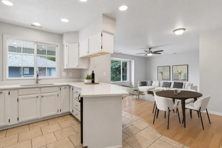 Open-concept kitchen featuring white cabinetry, light-toned countertops, and a stainless steel sink with a gooseneck faucet