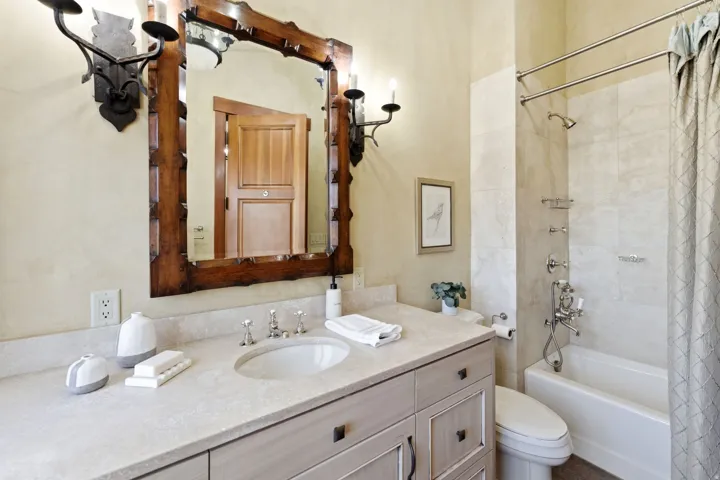 Bathroom vanity featuring an integrated sink with brushed nickel fixtures, a light-toned countertop, and a decorative wood-framed mirror