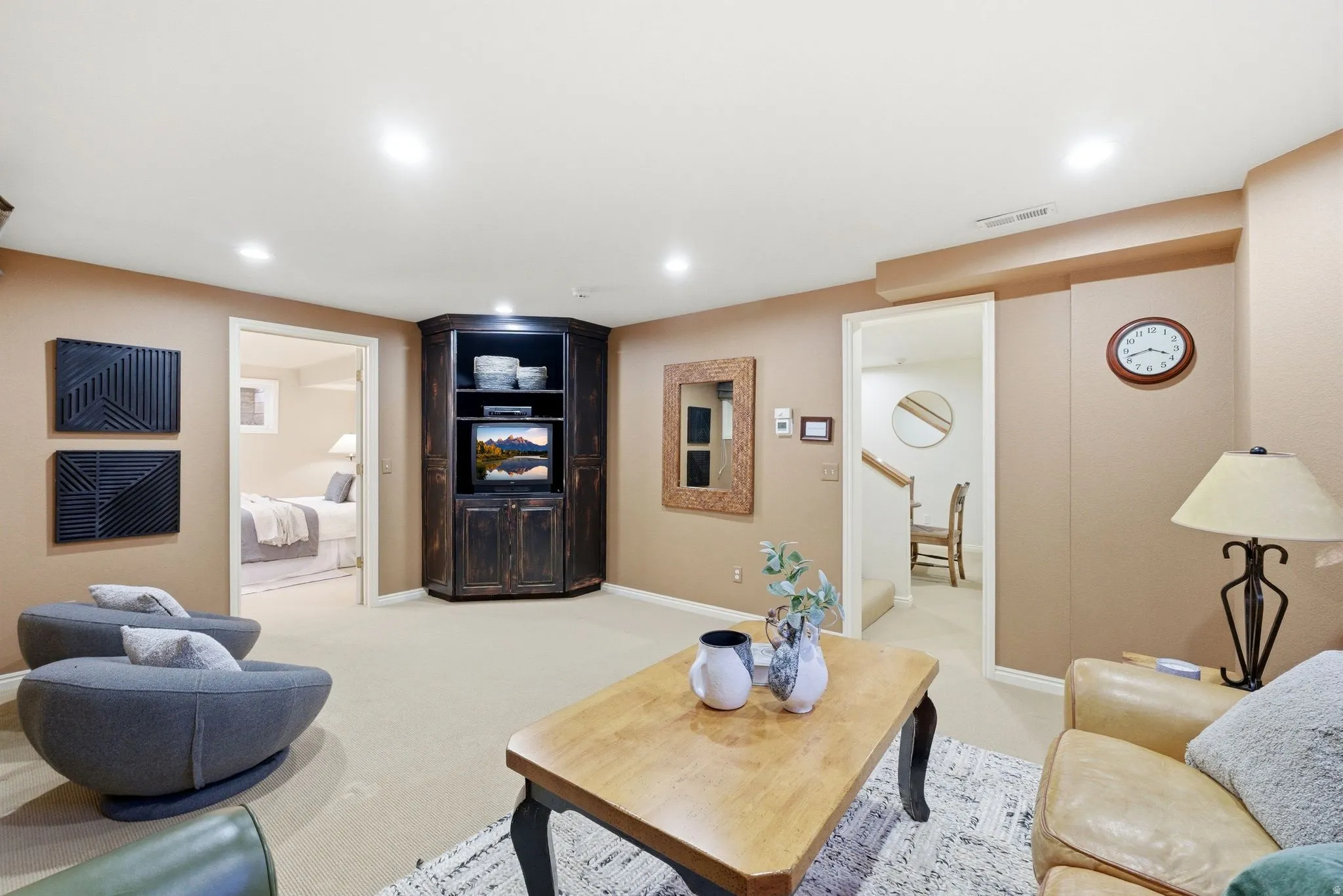 Carpeted recreation room featuring recessed lighting, a built-in corner media cabinet with open shelving, and a doorway opening to a bedroom