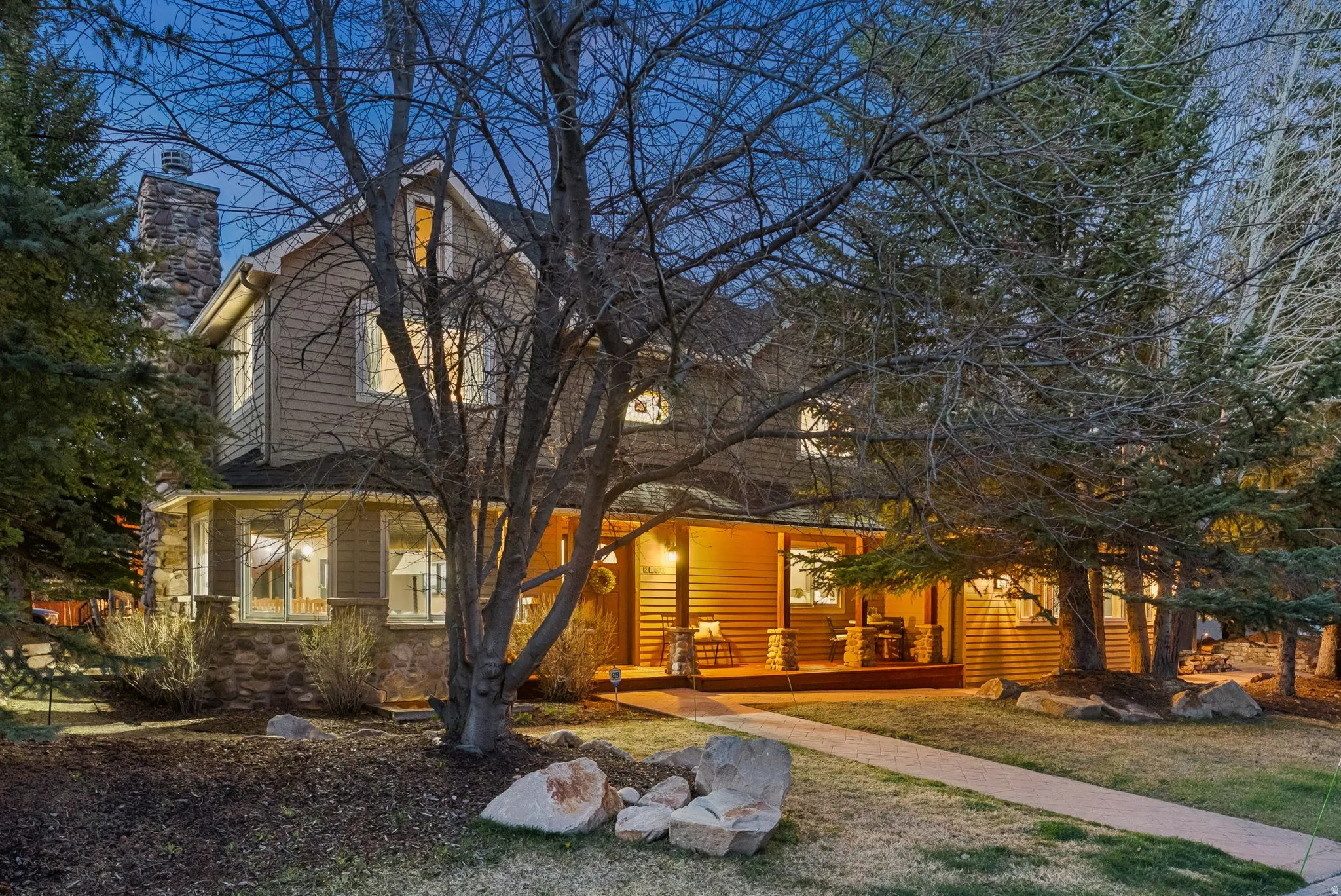 Exterior featuring a stone chimney, covered porch with recessed lighting, and a composite decking surface